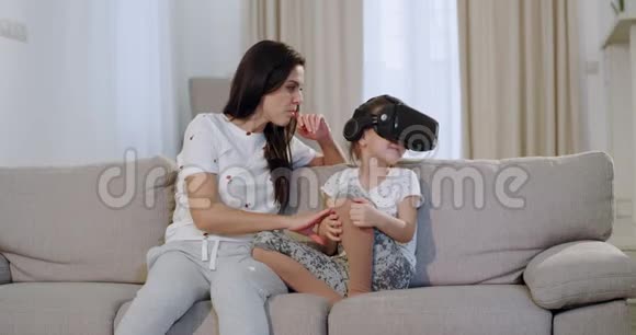 漂亮的母亲和女儿一起在沙发上度过了美好的时光她看着女儿视频的预览图