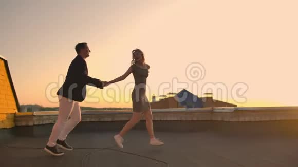 年轻夫妇牵着手走着女人牵着男朋友在屋顶的建筑日落POV概念视频的预览图
