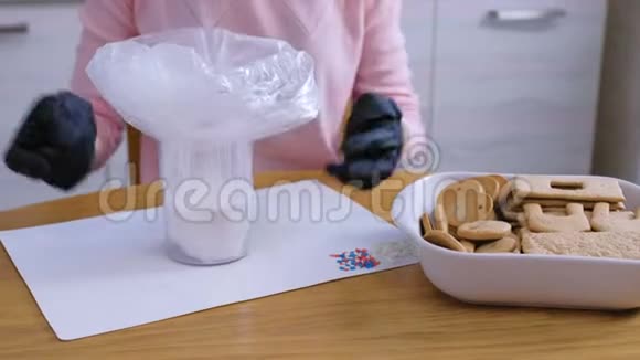 女人手拿着袋子里的糖糖糖霜来装饰饼干和姜饼屋烹饪视频的预览图