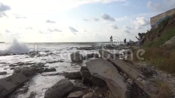 人们在海上看日落海浪冲破海岸上的岩石视频的预览图