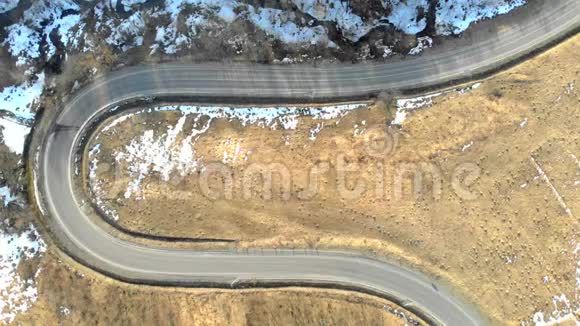 从冬季山区蛇形公路顶部的空中俯瞰以及在公路上行驶的汽车视频的预览图
