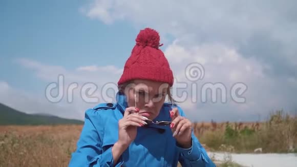 金发女郎玩得很开心站在一件蓝色的外套里一顶红色的帽子尖叫着手里拿着一个木棍摇晃着视频的预览图