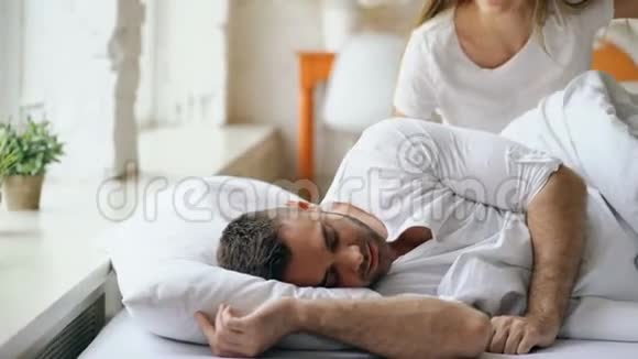 迷人的女人在床上亲吻和拥抱他的丈夫很有趣年轻美丽可爱的一对在视频的预览图
