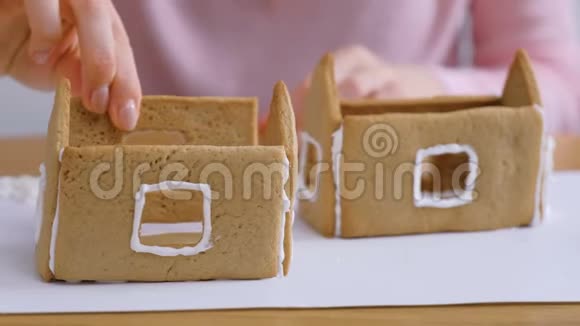 女人手使姜饼屋的细节与糖甜糖霜烹饪自制姜饼屋视频的预览图