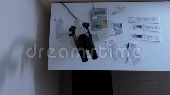 女实验室技术人员来到诊所的桌面坐在显微镜下视频的预览图