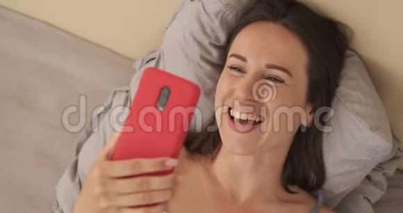 在床上玩手机视频聊天的女人视频的预览图
