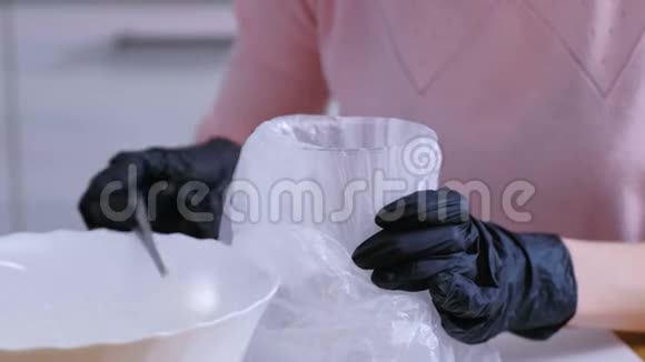 女人手把糖糖糖霜放在袋子里用来装饰饼干和姜饼屋烹饪视频的预览图