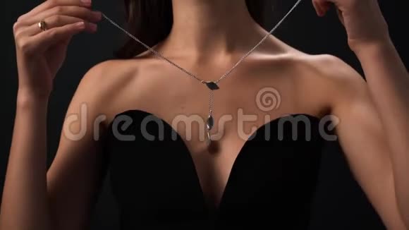 跟随一段镜头在一个漂亮的女孩或女人的脖子上戴着一条漂亮的项链穿着一件黑色的连衣裙带着一条深深的项链视频的预览图