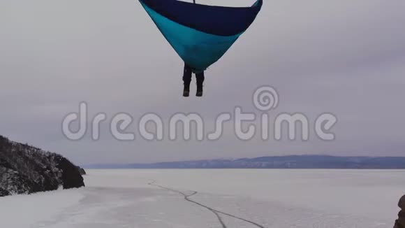 一个人坐在一个高海拔的吊床上在一个冰冻的湖上视频的预览图