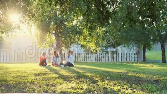 三个女孩的朋友在早上慢跑锻炼后坐在草地上聊天视频的预览图