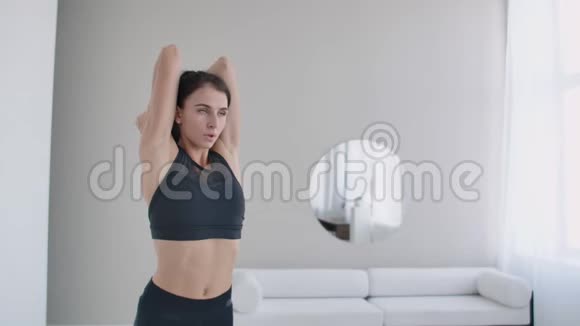 一个年轻的女孩用哑铃举起手臂从她的头后面做三头肌练习三头肌训练视频的预览图