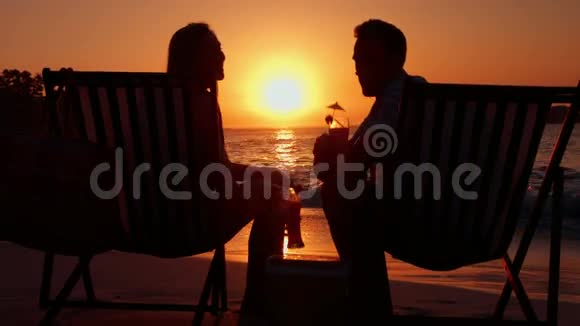 日落时分一对夫妇在海滩上喝酒视频的预览图