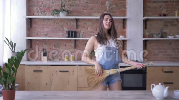 一般的清洁疯狂的家庭主妇在家务劳动中拿着像吉他一样的扫帚视频的预览图