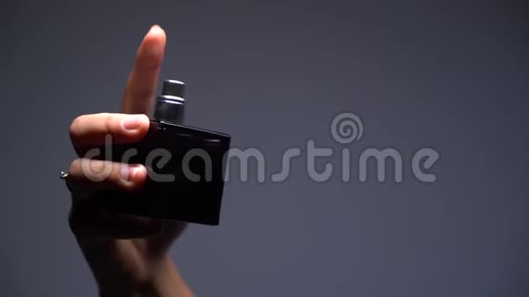一个女孩在黑暗背景上喷洒香水的特写慢动作剪影视频的预览图