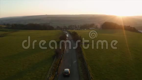 车辆行驶在狭窄的乡间小路上的空中镜头视频的预览图