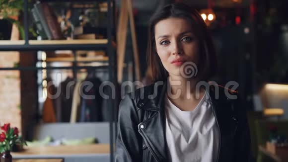 自信的女孩嬉皮士看着独自站在咖啡馆里的镜头的肖像视频的预览图