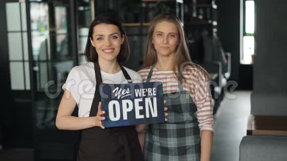 美丽的企业主在咖啡馆里微笑着举着开放标志的画像视频的预览图