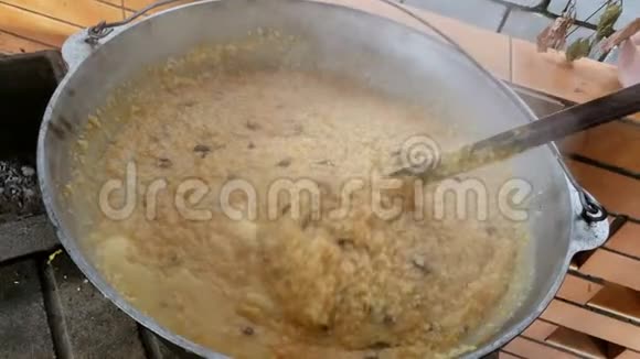 用大锅勺搅拌传统粥准备慈善餐视频的预览图