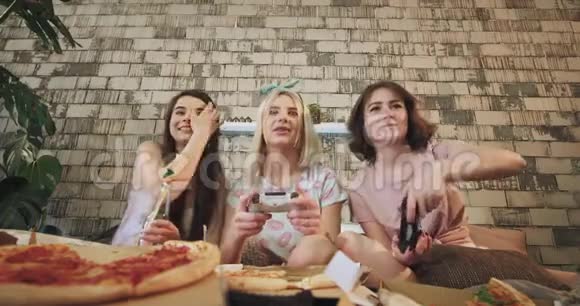 在现代化的卧室里有着美丽的设计三位朋友的女士在PlayStation玩非常喜欢吃披萨视频的预览图