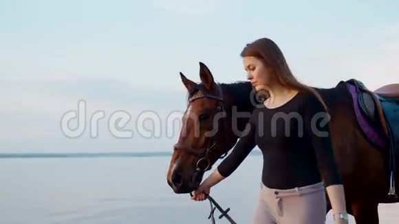 女孩牵着一匹马沿着海岸日落时骑着马的女孩视频的预览图