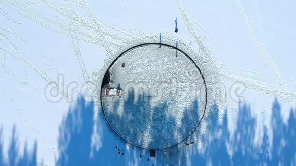 一个巨大的雕刻圆洞的俯视图一个连接的马达使它旋转人们骑在一个大浮冰上长长的影子视频的预览图