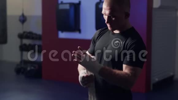 野蛮拳击手在战斗前用弹性绷带包住双手动作缓慢光线低的场景视频的预览图