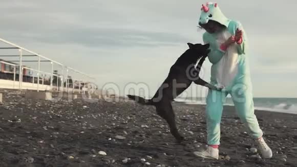 一位穿着吉古鲁米服装的快乐女士正和一只狗在海边玩得很开心视频的预览图