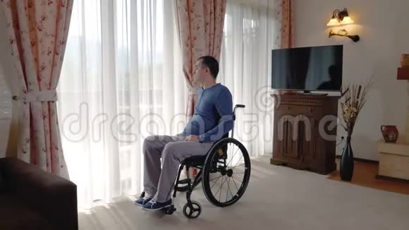 坐在轮椅上的悲伤青年透过窗户看着视频的预览图