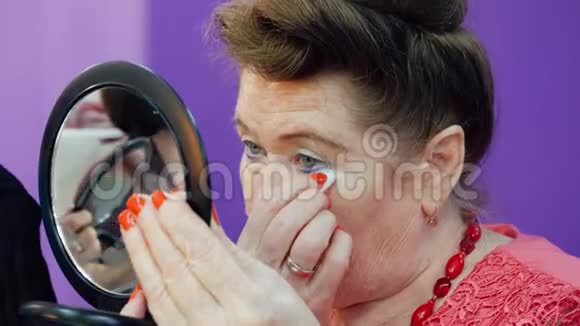 一位年长的女士用眼睛化妆脸前小镜子闭上视频的预览图