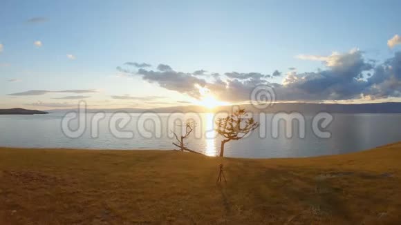 三脚架上的摄像机拍摄日落时的风景海景空中射击视频的预览图