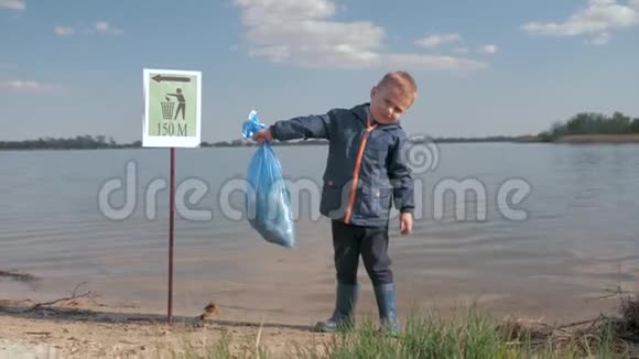大自然中的生态污染垃圾清理塑料垃圾后手拿垃圾袋的小男孩画像视频的预览图