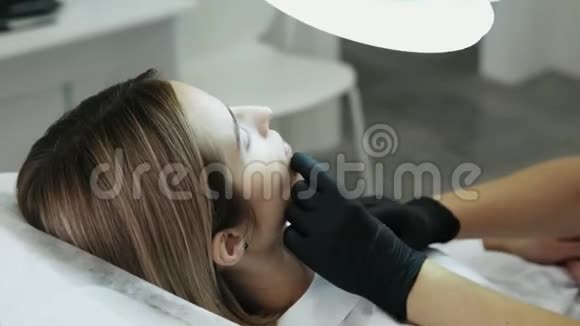 特写侧景女人她的脸和美容师用注射器的手做面部美容注射视频的预览图