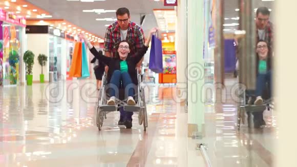 一个男人在购物中心买了一个坐轮椅的残疾妇女后很幸运他们在玩他们在笑慢节奏视频的预览图