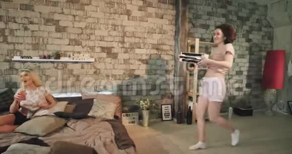 少女们晚上穿着睡衣参加家庭聚会女士带着一个披萨盒跑过来把它们带到床上视频的预览图