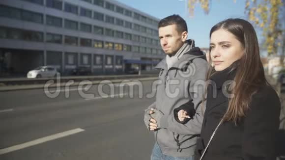 年轻夫妇站在路边男人不自信地搭出租车搭便车视频的预览图