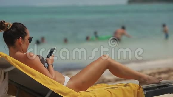带着手机在海滩上的女孩视频的预览图