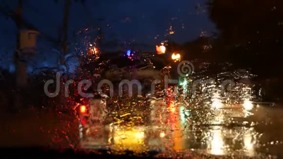 泰国松塔尤巴士与照明前灯沿夜间街道在雨季从汽车玻璃中观看视频的预览图