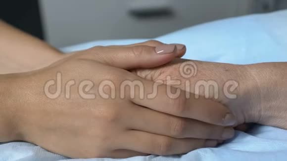 爱的女儿牵着熟睡的母亲的手在医院的房间里感到担心视频的预览图