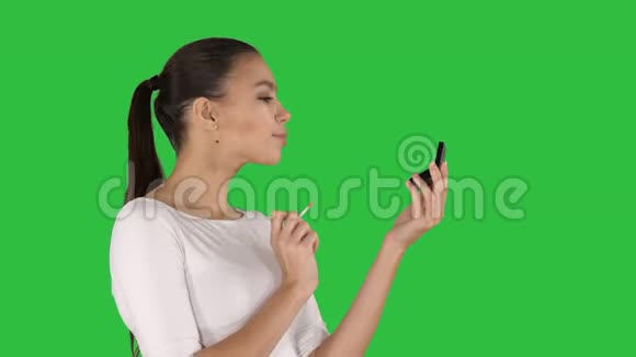 漂亮的年轻女人在绿色屏幕上涂口红铬钥匙视频的预览图