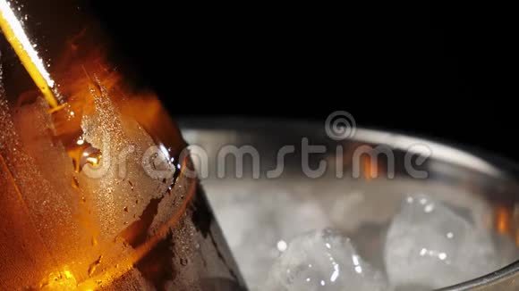 新鲜啤酒用勺子把冰冷的冰倒进一桶美味的手工啤酒放在棕色的瓶子里背景是黑色的视频的预览图