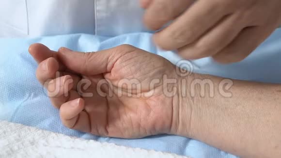 医生在手术后触摸病人失去知觉的手检查脉搏帮助视频的预览图
