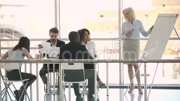 中年女商人教练在会议室的白板上展示视频的预览图
