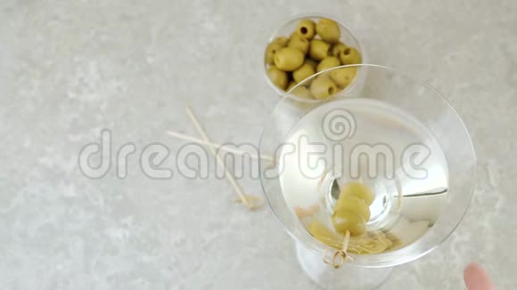 豪华马提尼手拿一杯带有橄榄和鸡尾酒棒装饰的桌子上的甜马提尼视频的预览图