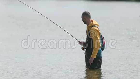 渔夫抛着浮子把鱼从河里拉出来站在水里视频的预览图
