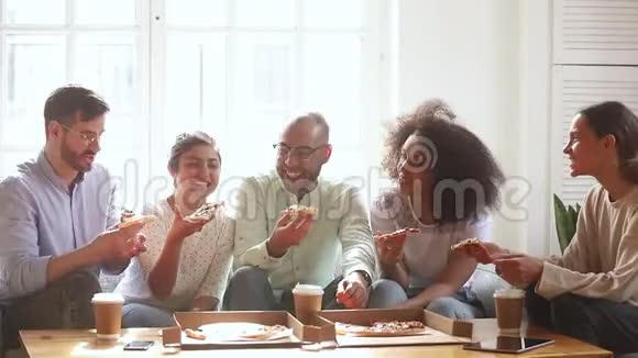 快乐的多种族年轻人在室内笑着吃披萨视频的预览图