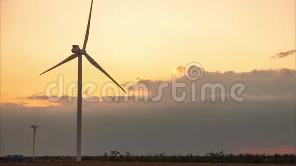两台风力发电机在夕阳和巨大的云层的背景下时光流逝视频的预览图