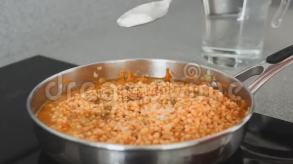 在平底锅里炖扁豆一只手拿着一勺香料出现在框架中调味料被添加到视频的预览图