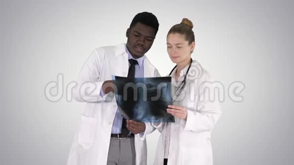 年轻的女医生和美国黑人医生在梯度背景下看肺的x射线照片视频的预览图