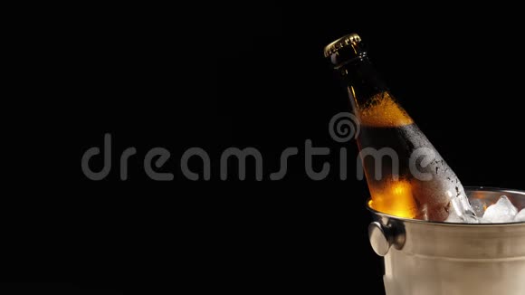 新鲜啤酒用勺子把冰冷的冰块倒入一桶棕色的啤酒里视频的预览图