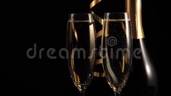好香槟酒两杯金香槟酒和一瓶香槟酒木桌上放着金色的丝带视频的预览图